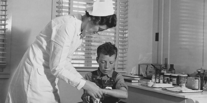 Old timey nurse treating young boy's wrist injury