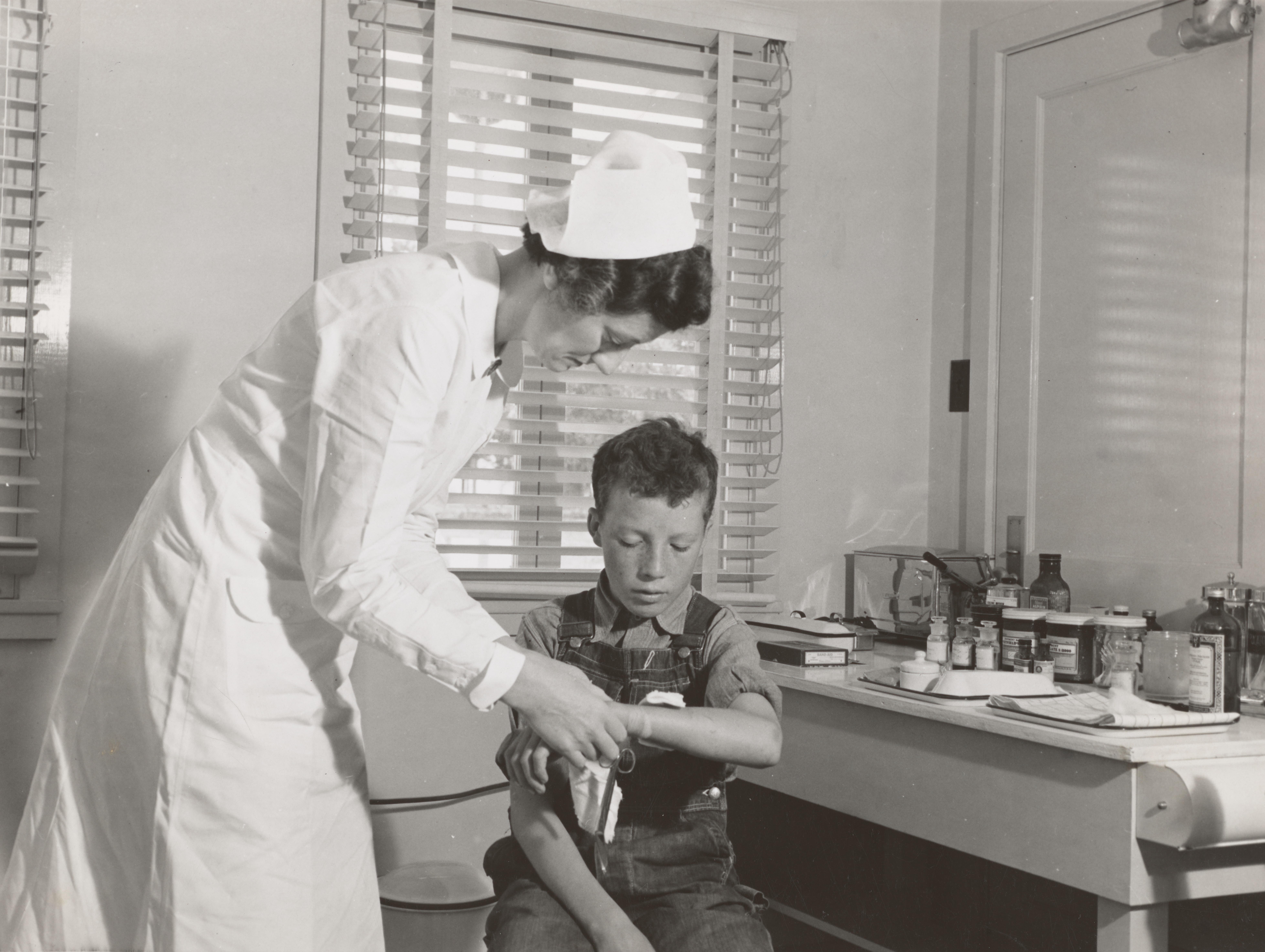 Old timey nurse treating young boy's wrist injury