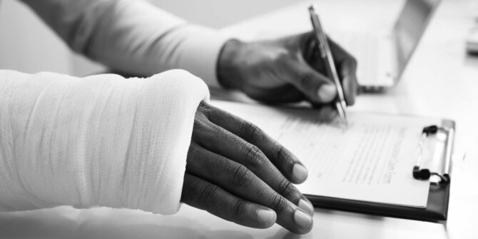 Person with a broken arm signing document on clipboard