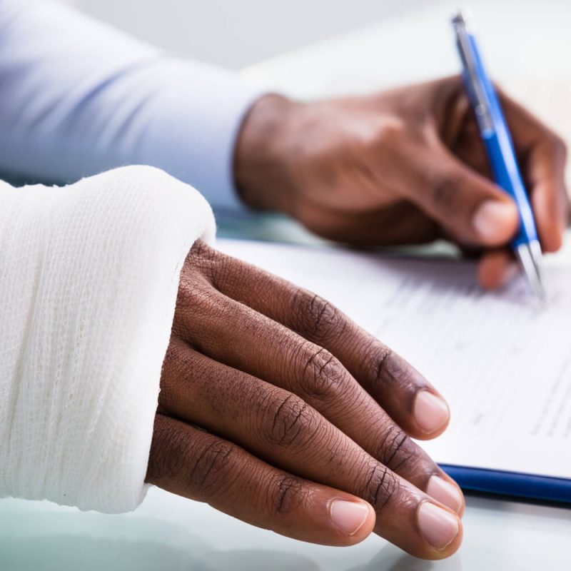 Person with a broken arm signing document on clipboard