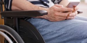 Man in wheelchair's hands texting on smartphone