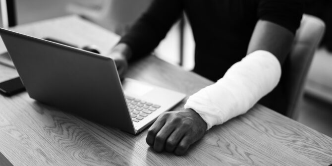 Man with borken arm typing on laptop