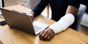 Man with borken arm typing on laptop