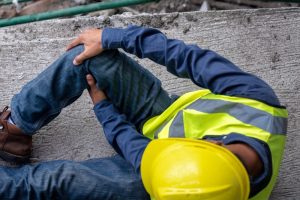 Construction worker clutching his knee on pavement