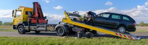 Damaged black vehicle on flatbed yellow tow truck
