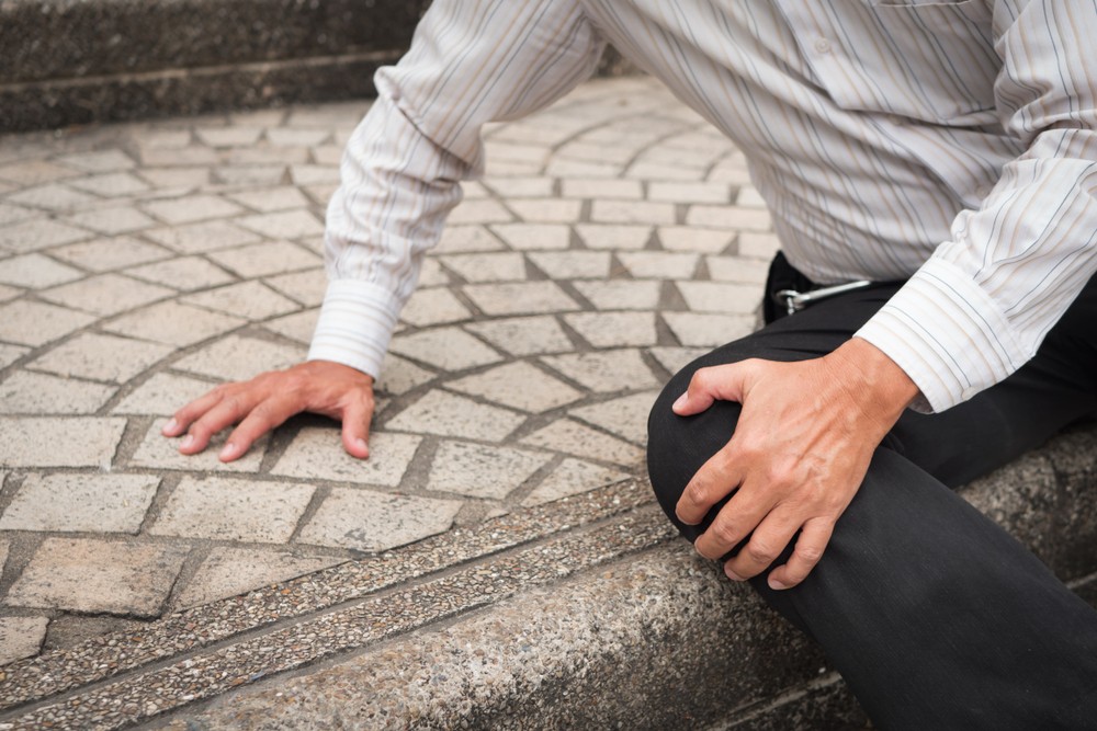 Man clutching his knee from falling on pavement