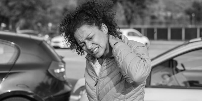 Woman in teal jacket clutching neck in pain