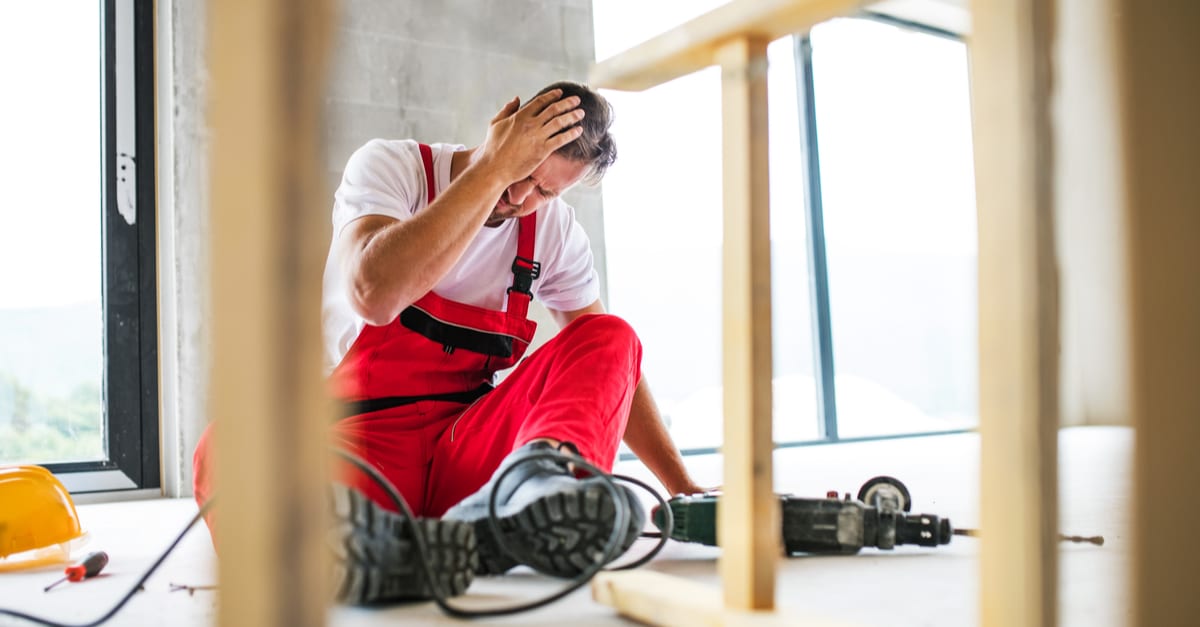 Seated construction worker holding head in pain