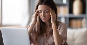 Woman sitting at computer holding her temples from frustration