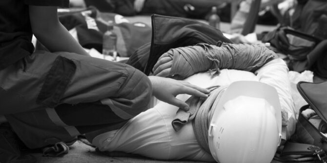 Injured construction worker laying down and being treated by emergency medical services