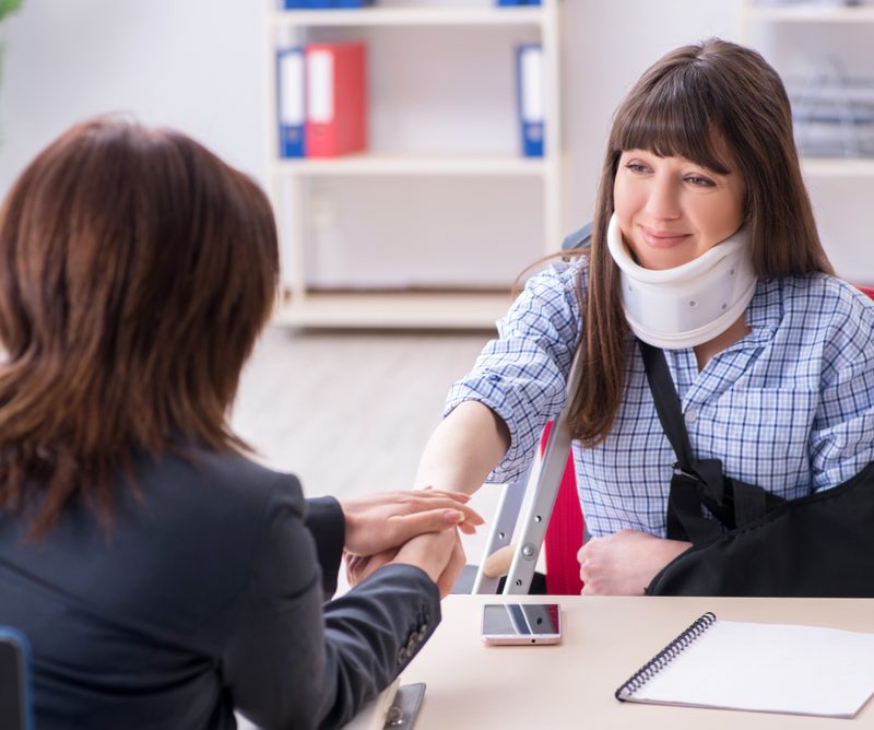 Woman in neck brace talking to workers compensation lawyer