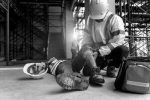 Construction employee laying on floor with hard hat and employee trying to help
