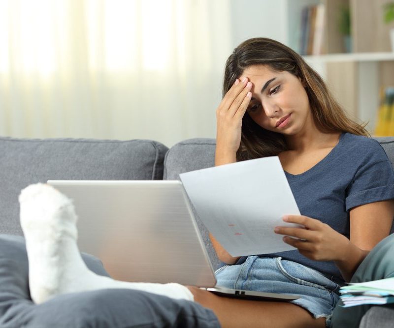 Injured woman sitting on couch frustrated with workers comp paperwork