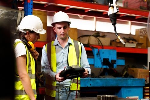 two maintenance engineers in hard hats and safety vests operating industrial equipment